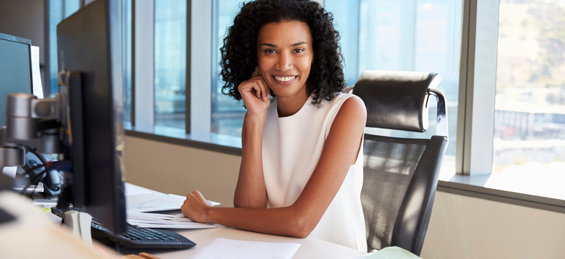 A paralegal sitting in an opulent office and smiling because she's made the right choice between public service and private practice.