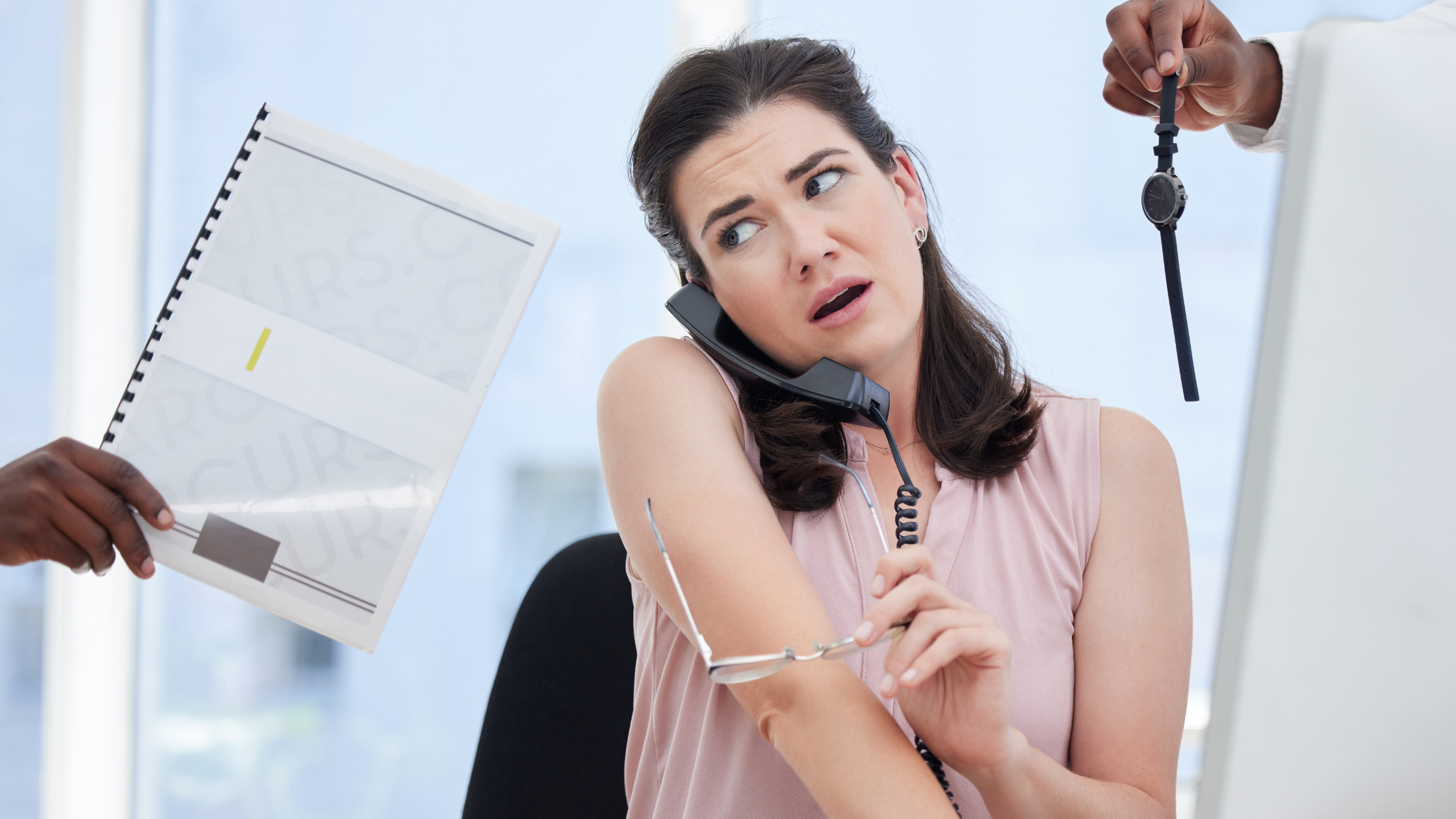 An overwhelmed paralegal receiving a client's call while she's working on other clients' documents.