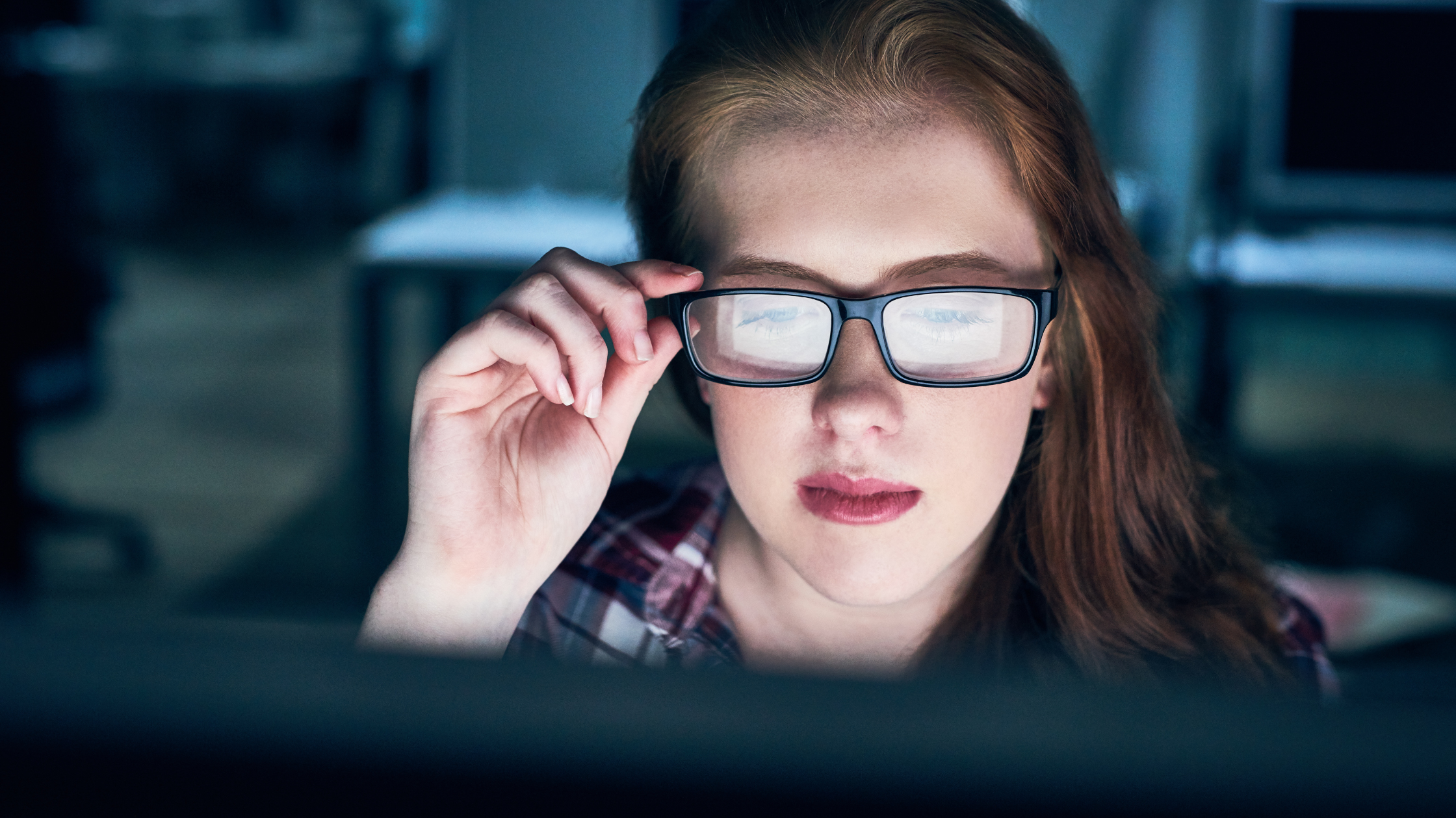 An attorney sits before a computer and holds her glasses as she peruses different paralegals' résumés.