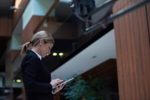 A businesswoman pressing her tablet on the ground floor while she awaits the elevator