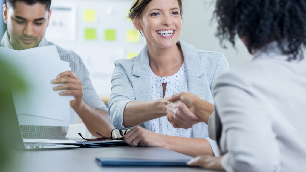 A paralegal shakes hands with a client and smiles as a way of managing clients and their expectations.