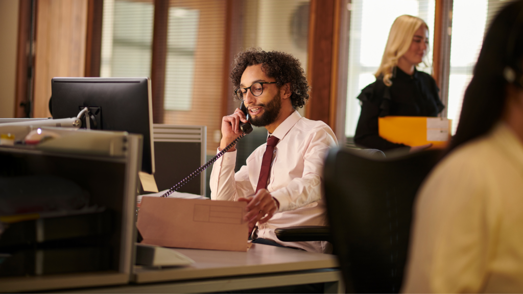 A busy paralegal handling clients' calls and works on his PC, demonstrating if it's worth it to become a litigation paralegal.