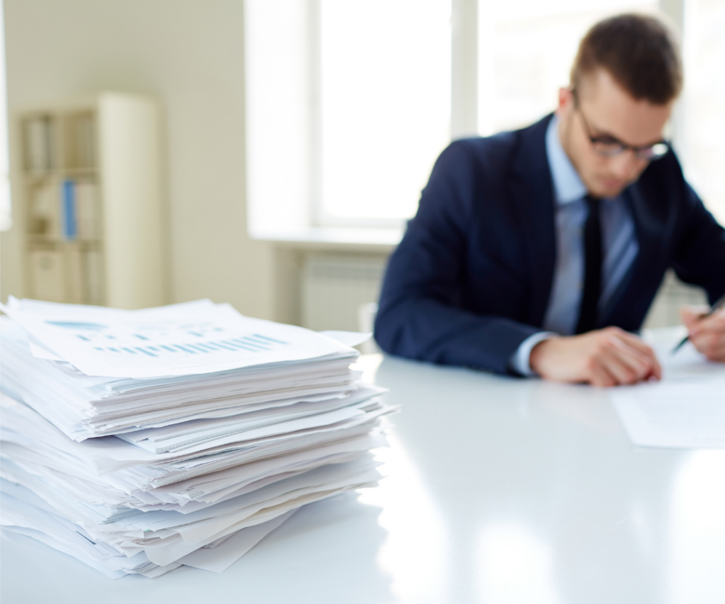 Man working on a stack of contracts with completed papers on the desk