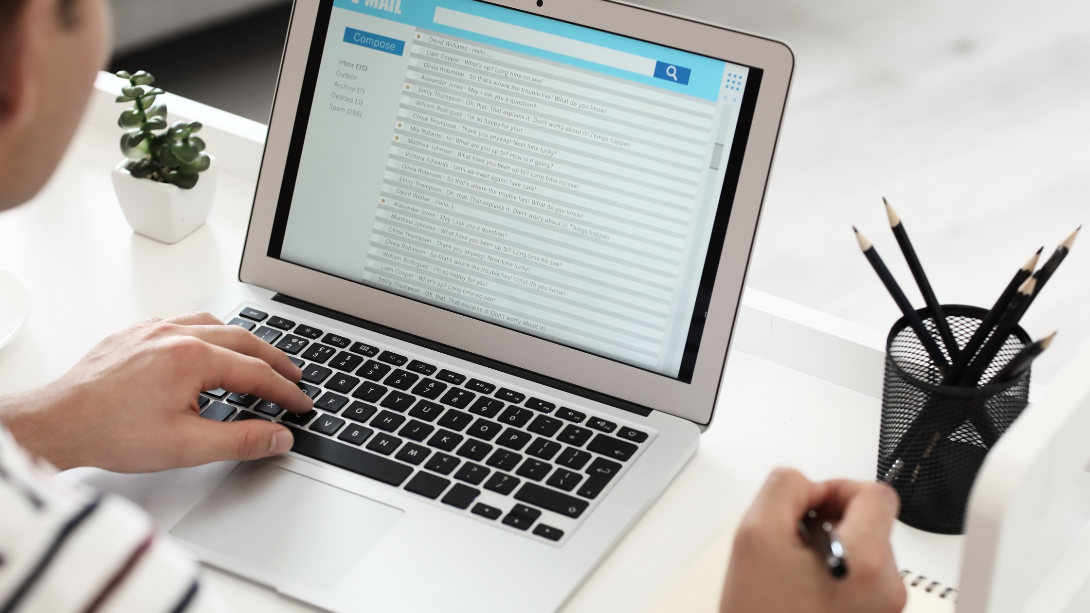 A litigation paralegal sits at her desk and works on her computer while she jots some points in her notepad.