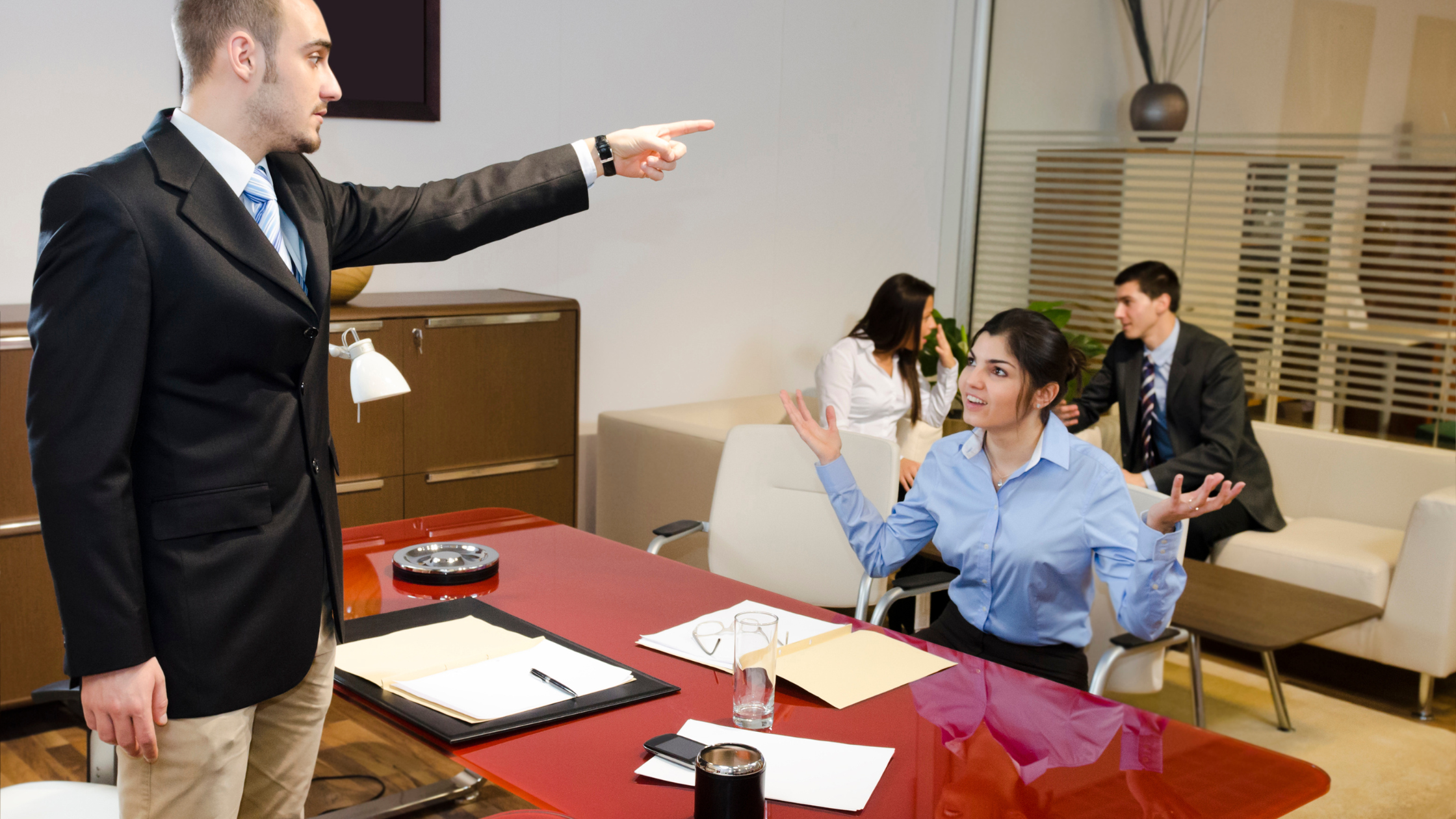 A paralegal manager stands over a paralegal and points her to the door depicting she has lost her job.