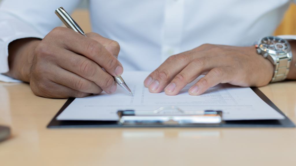 A paralegal sits at a desk, reads a client's medical records and summarizes in a paper on his clipboard.