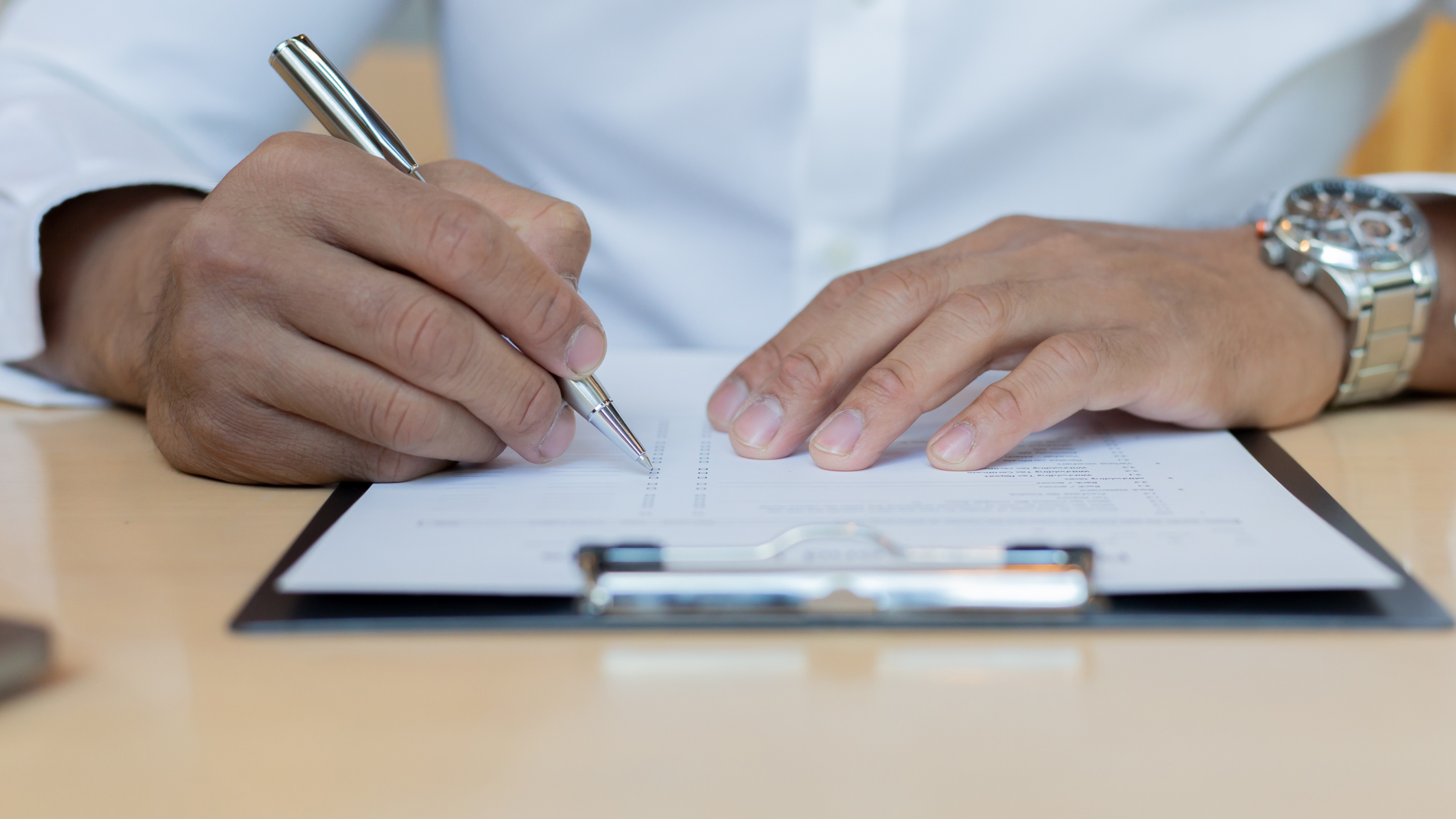 A paralegal sits at a desk, reads a client's medical records and summarizes in a paper on his clipboard.