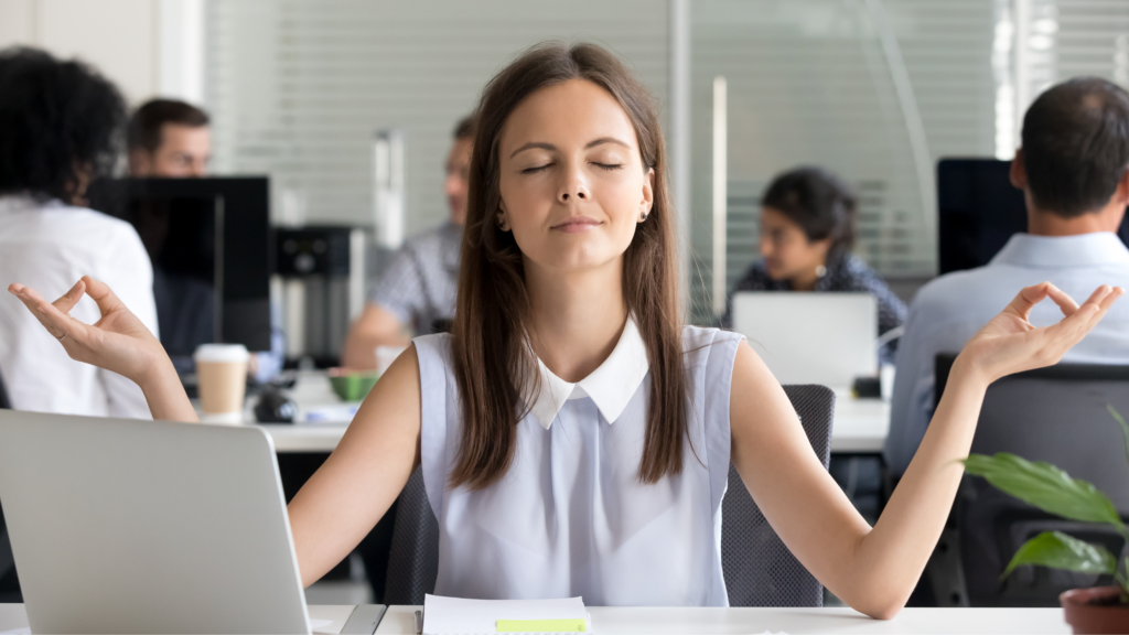 A paralegal sits and practices mindfulness at her desk to check stress.