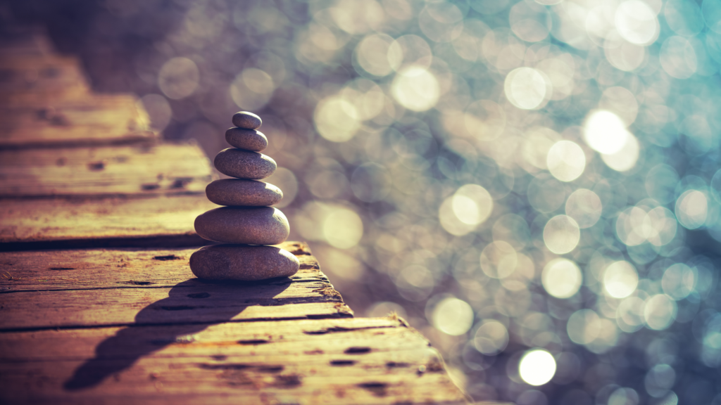 Stacked stones beside calm waters portraying how mindfulness can help paralegals reduce stress.