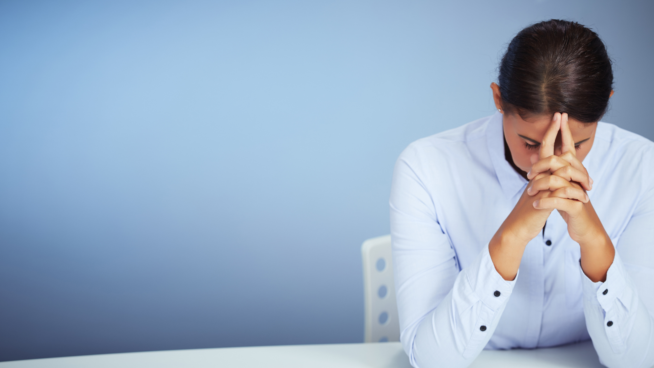 A paralegal rests her head on her hands as she ponders the effect of the negativity at her workplace on her performance.