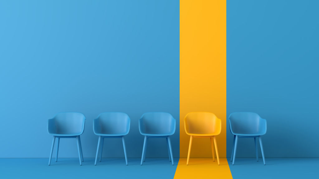 An image of chairs arranged along a wall with the same colors except one that stands out depicting the need for uniqueness.