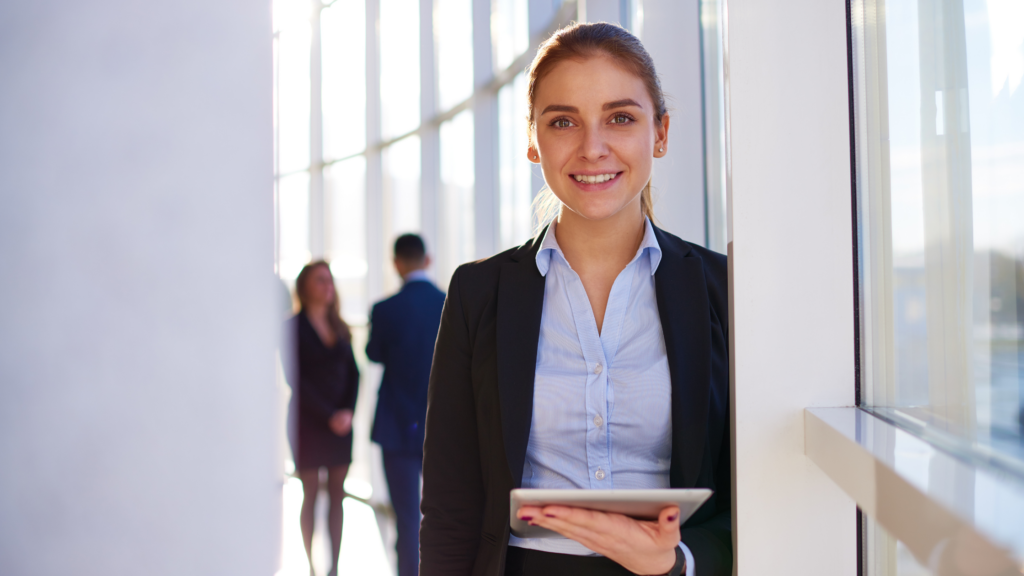 A paralegal intern stands by a window and smiles because she has learned how to turn her internship into a job offer.