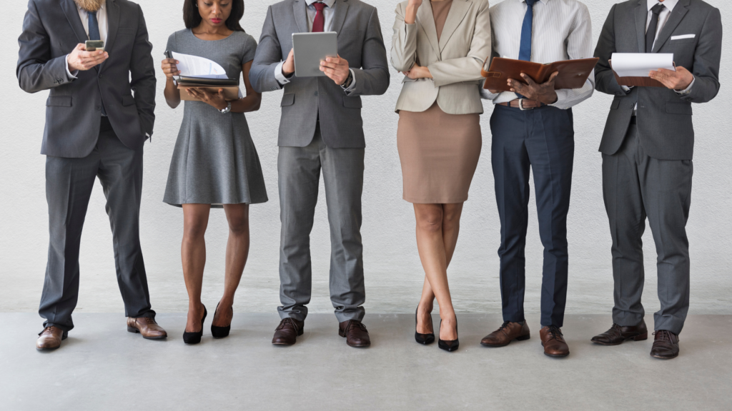 A group of paralegals peruse the papers in their hands, wondering if they should pursue a paralegal license to stand out.