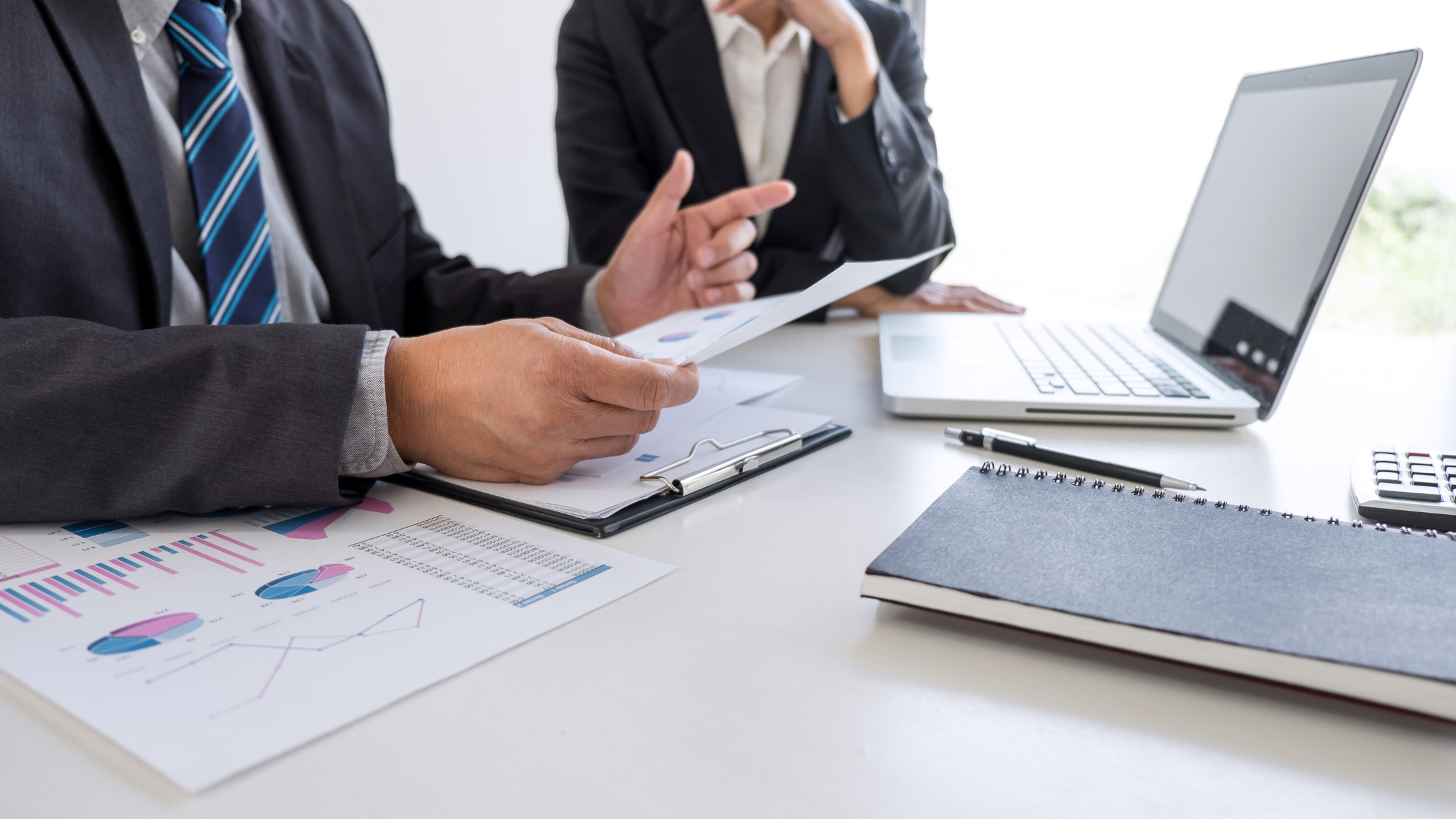 A paralegal manager sits with a new paralegal to explain some charts, demonstrating a con of being a paralegal manager.