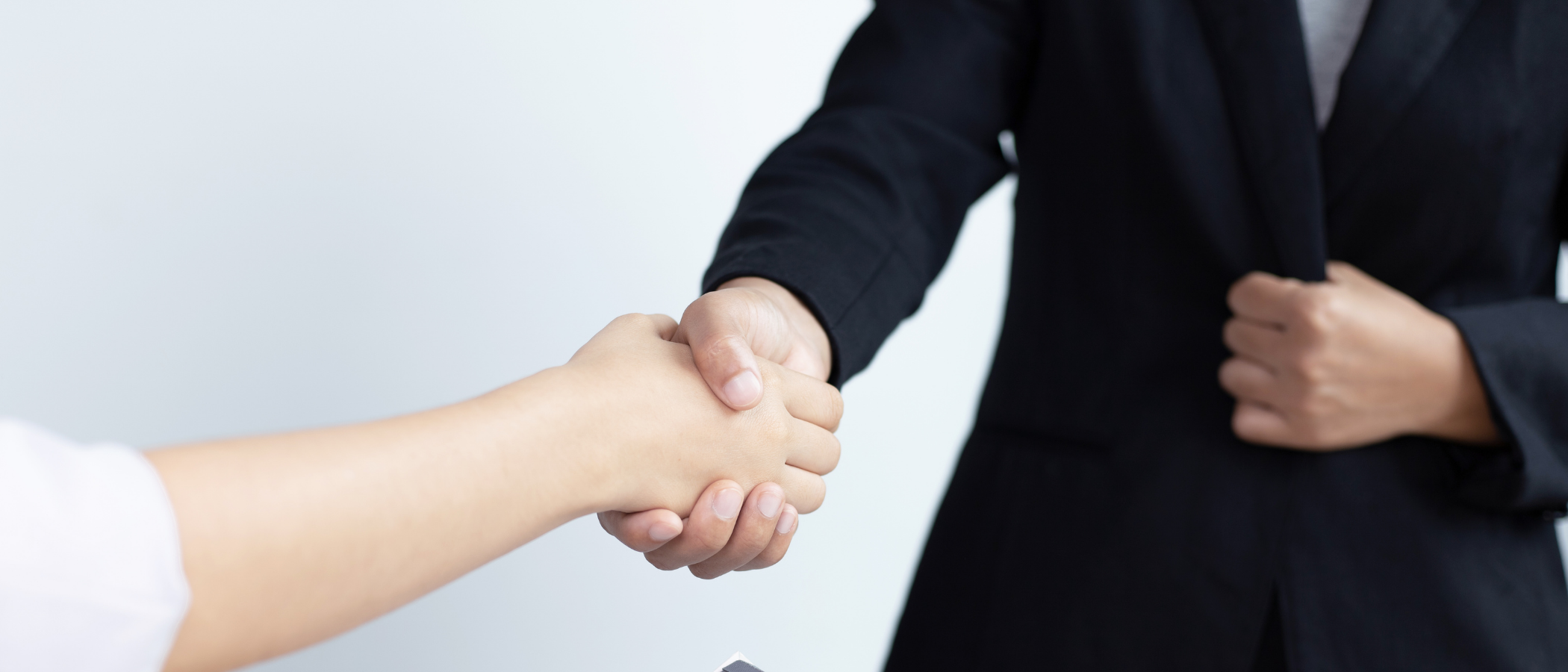 A paralegal and his client standing and having a firm handshake