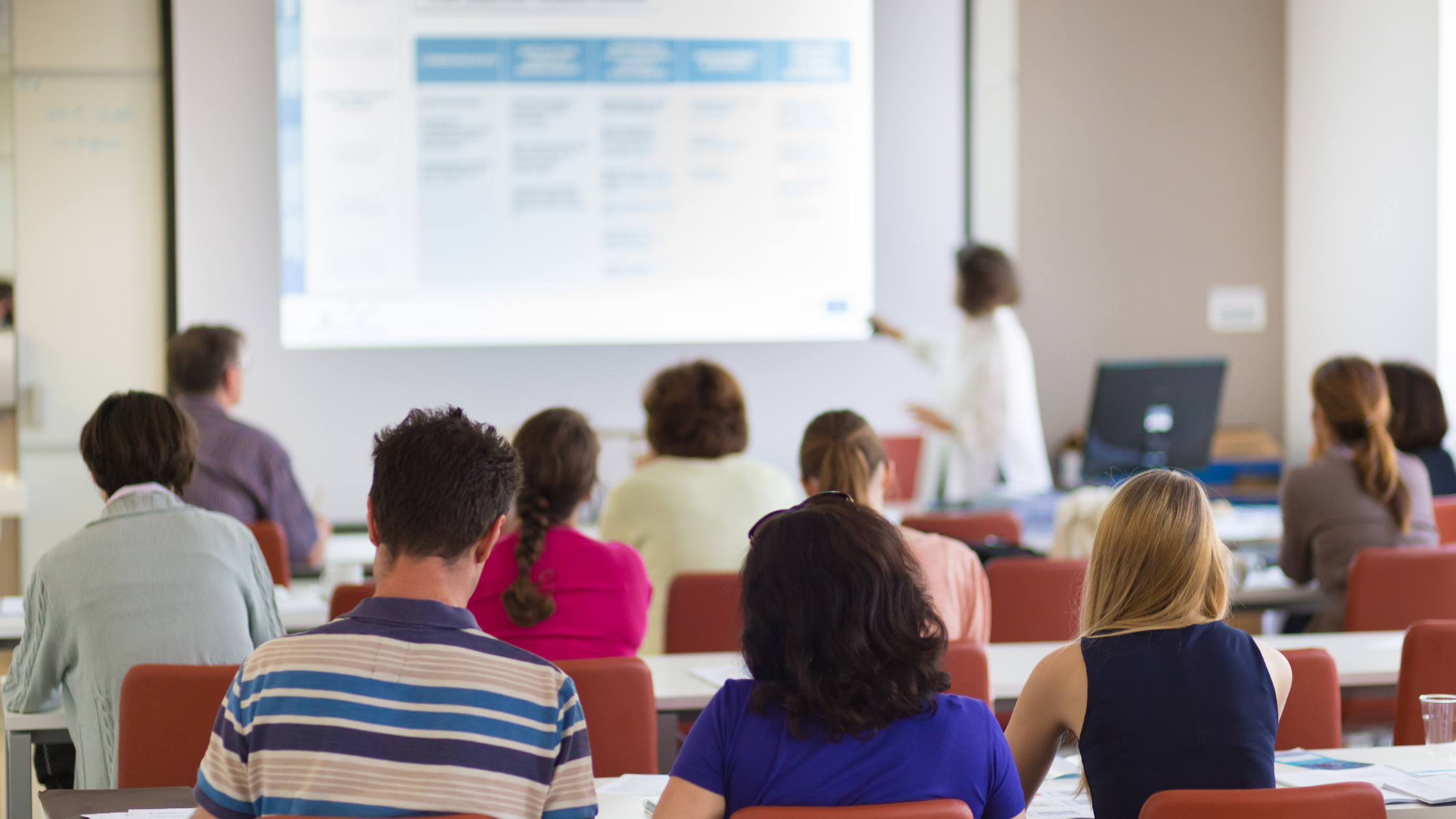 A group of paralegal students sitting in class and listening to their paralegal teacher offer information.