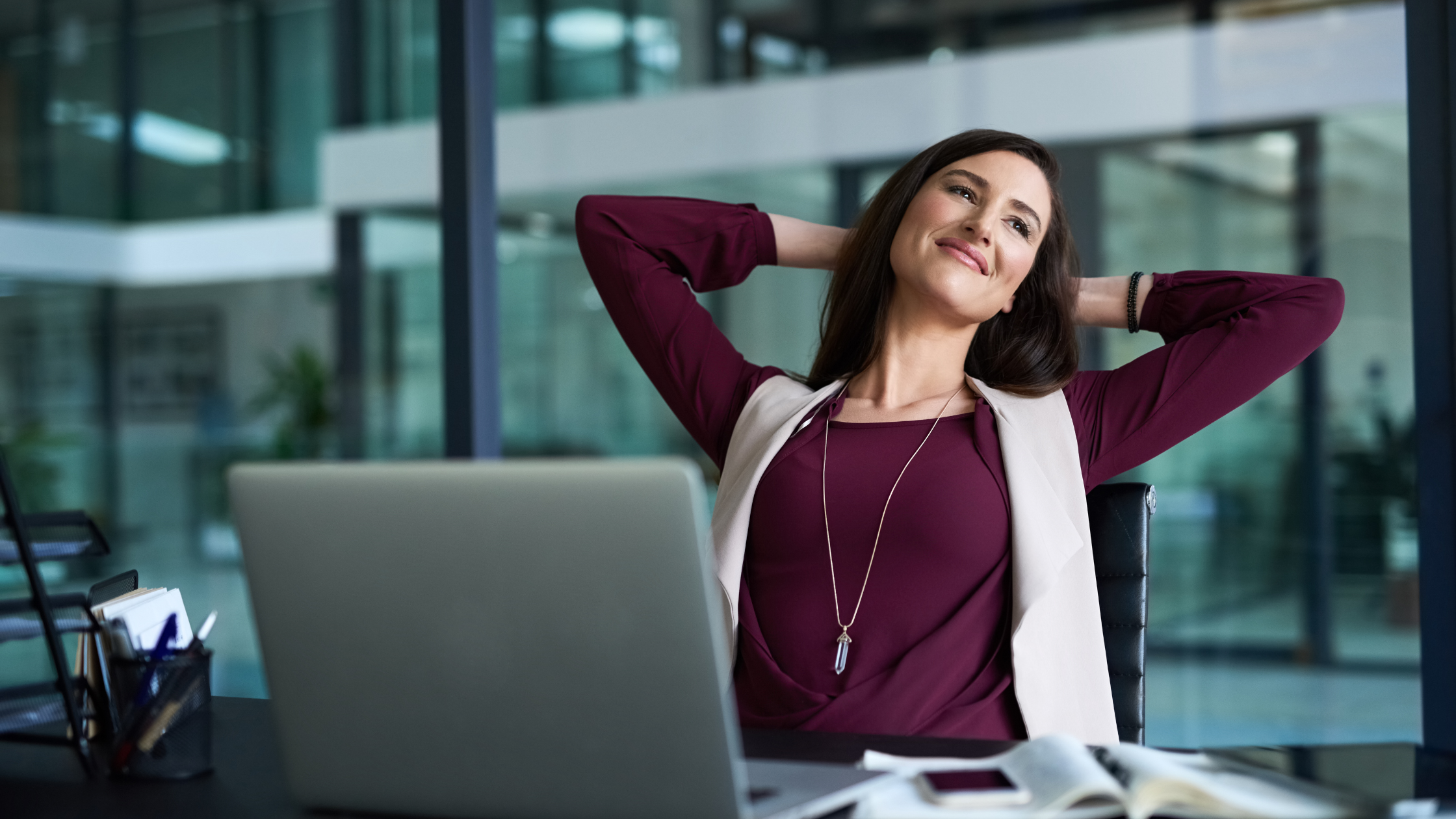 A professional paralegal sits at her desk and stretches, wondering if it's time for a break.