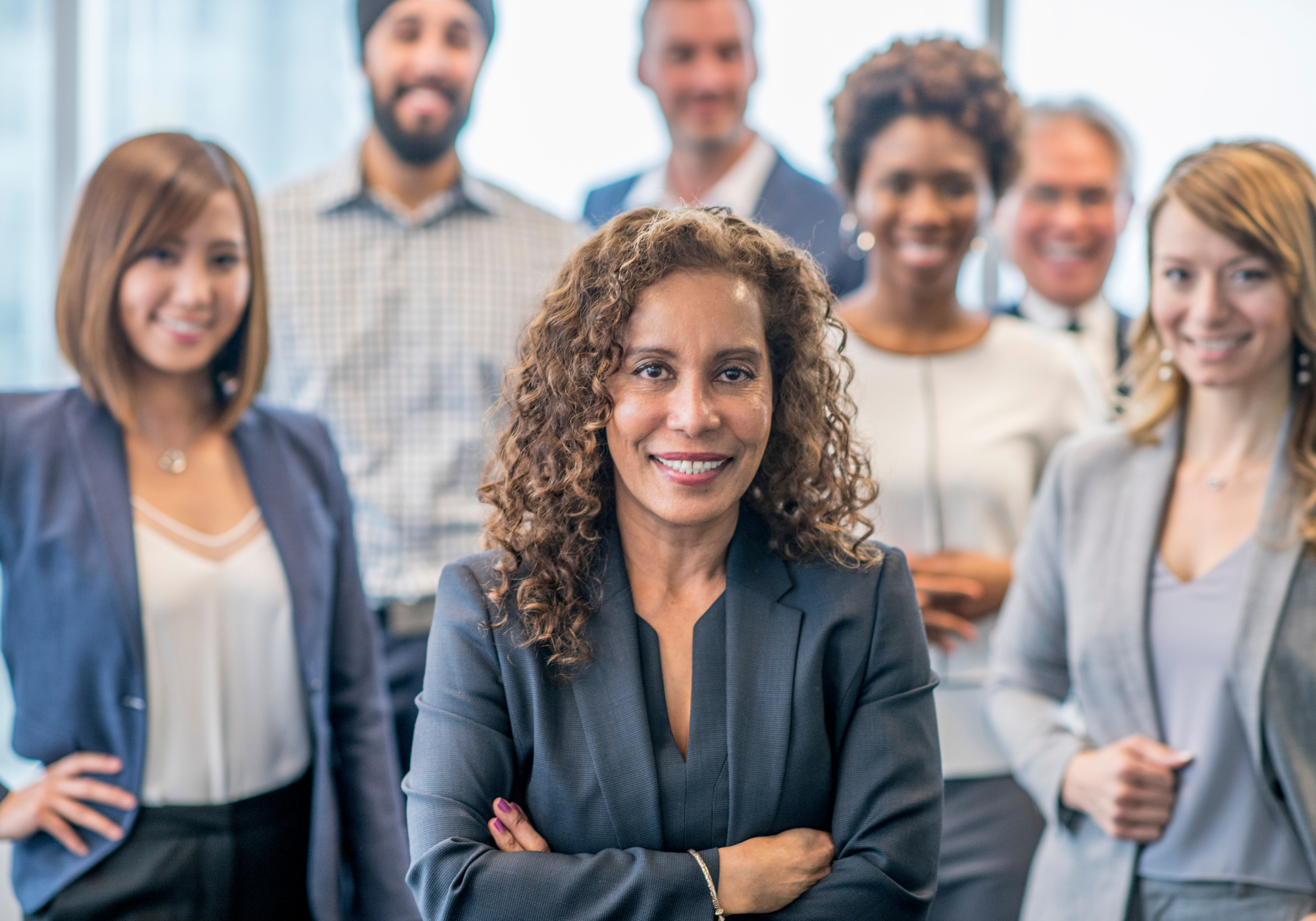 Female CEO smiling and standing in front of her team of experts