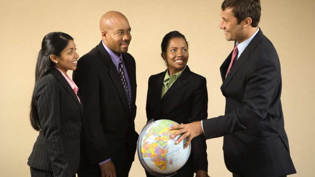 Paralegals from different countries stand together around a world map globe while one of them touches it.