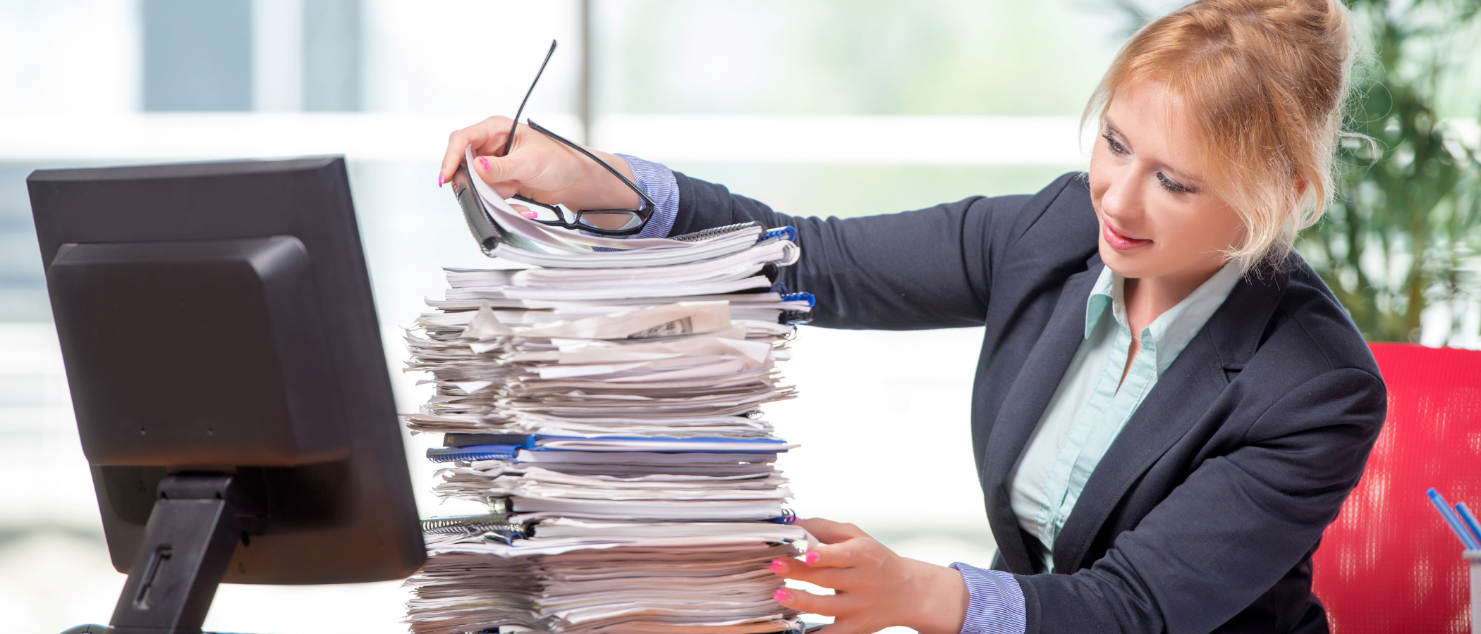 A red-hair woman going through a stack of files to get the necessary info