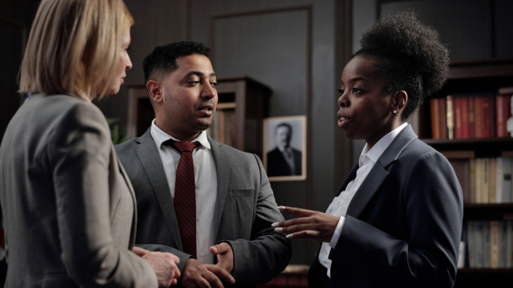 Three paralegals stand in an office and exchange ideas on how fulfilling a public defense paralegal is.