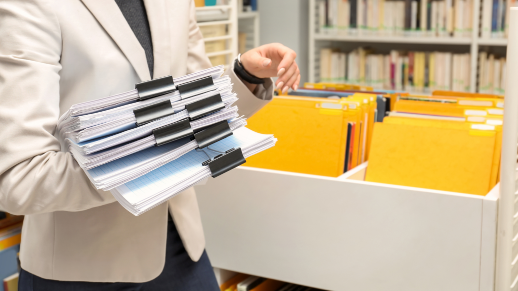 A paralegal stands in her office and removes some depositions from the drawer for a deposition summary.