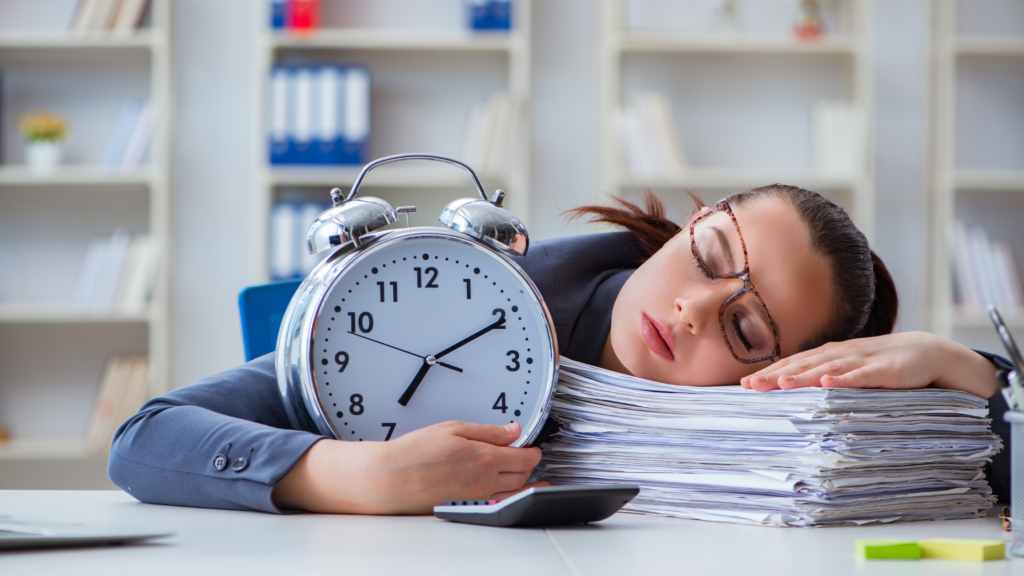 An exhausted paralegal sleeps on the documents she's working on while holding a clock on her table.