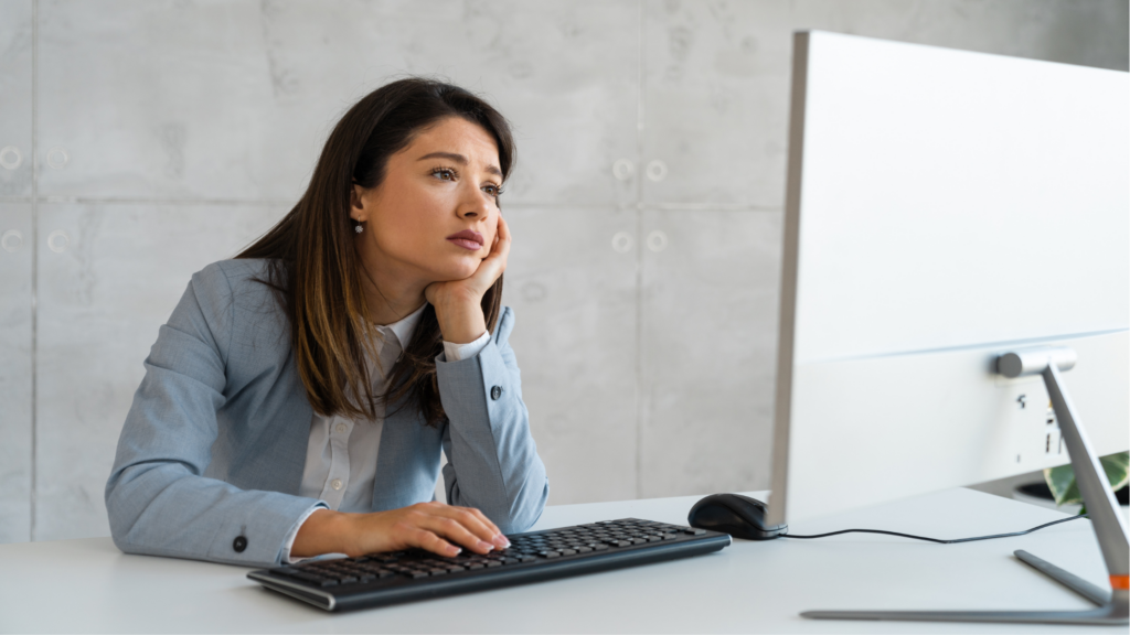 A professional paralegal sits and operates her computer while looking bored showing she's underutilized in her firm.