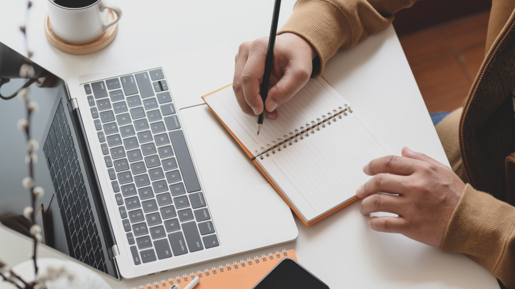 A paralegal sitting at her desk with a computer and writing down her five year plan.